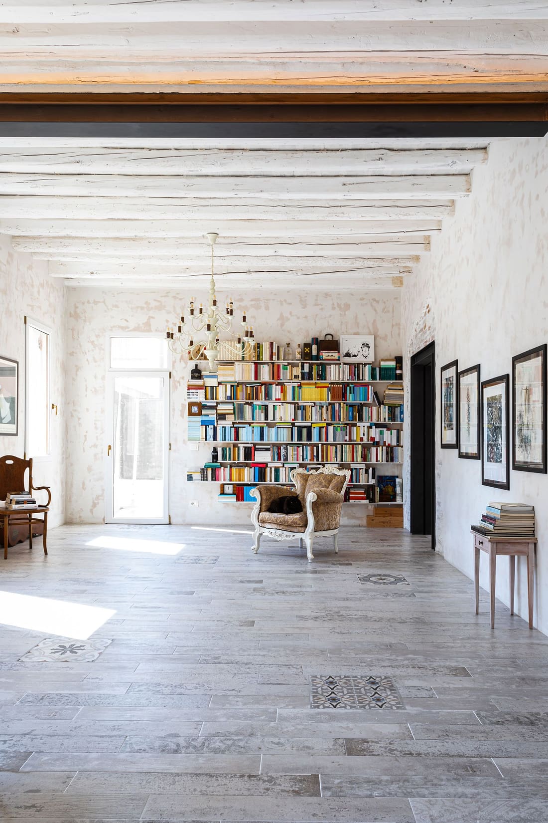 Parete di libri e poltrona sotto il lampadario